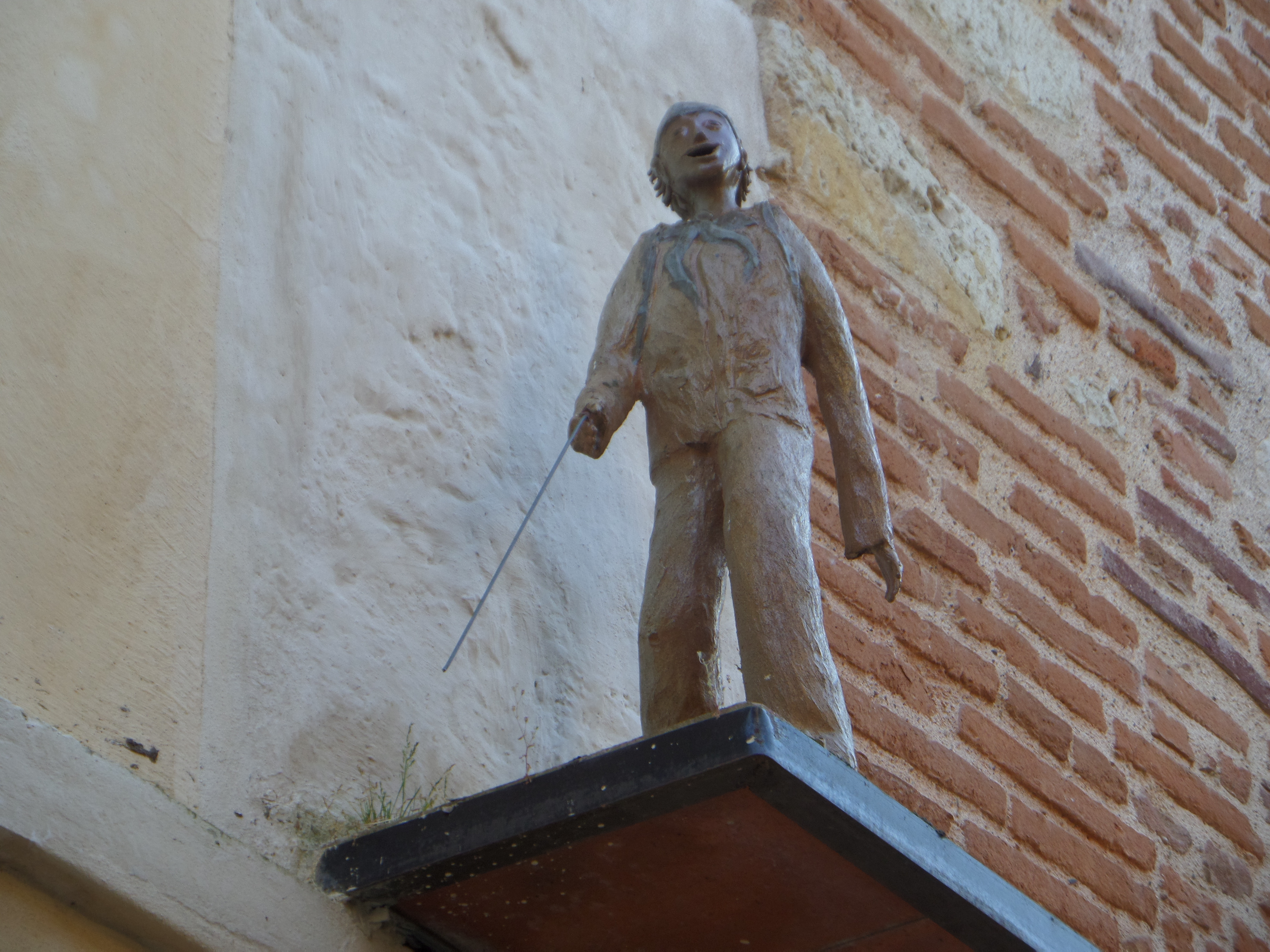 A low-angle shot of a carved pilgrim; in Auvillar, France, there are several carvings of these pilgrims in different styles.