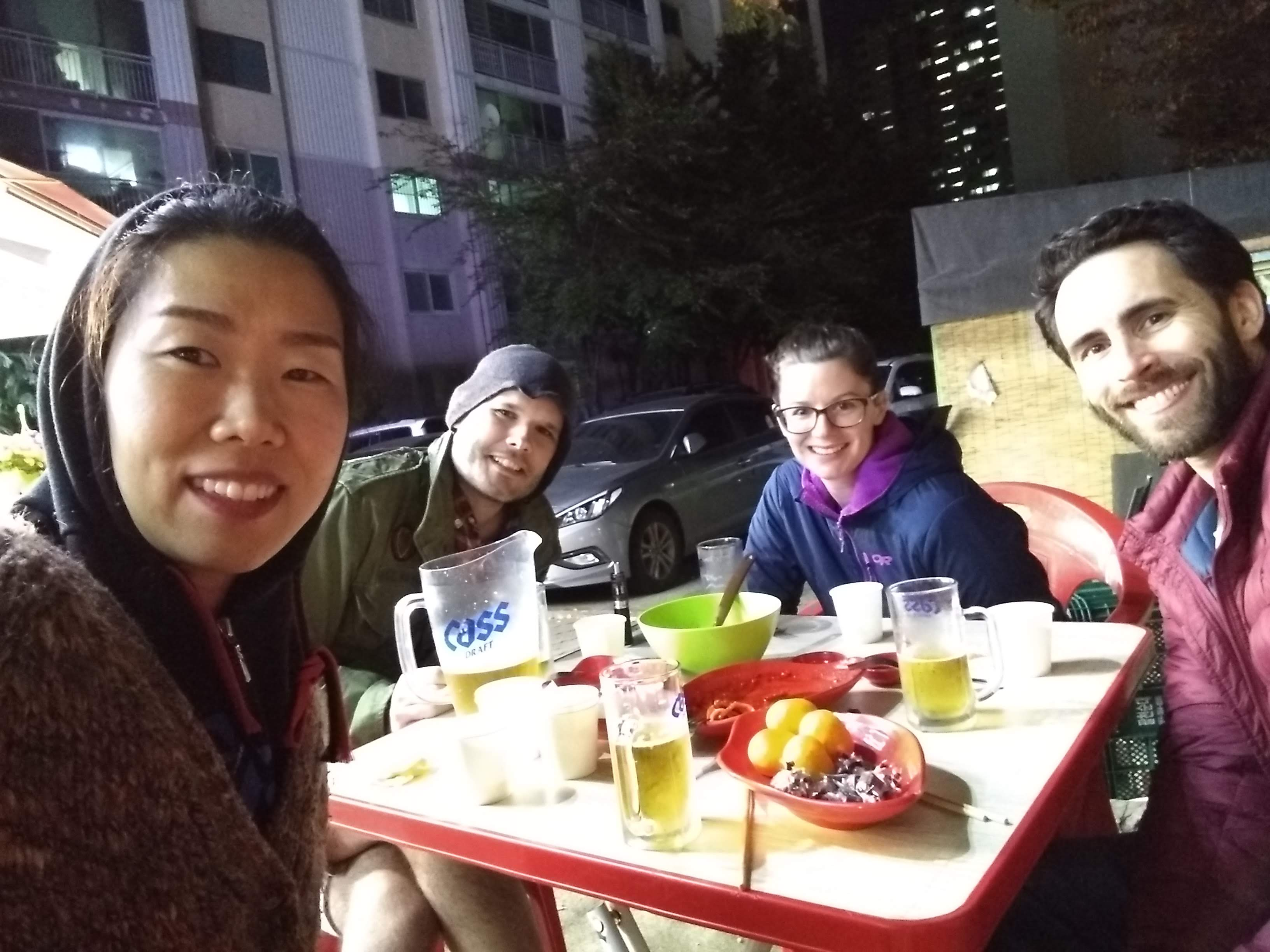 The author & friends in Busan, South Korea, eating snacks & drinking beer at a ddeokboggi stand