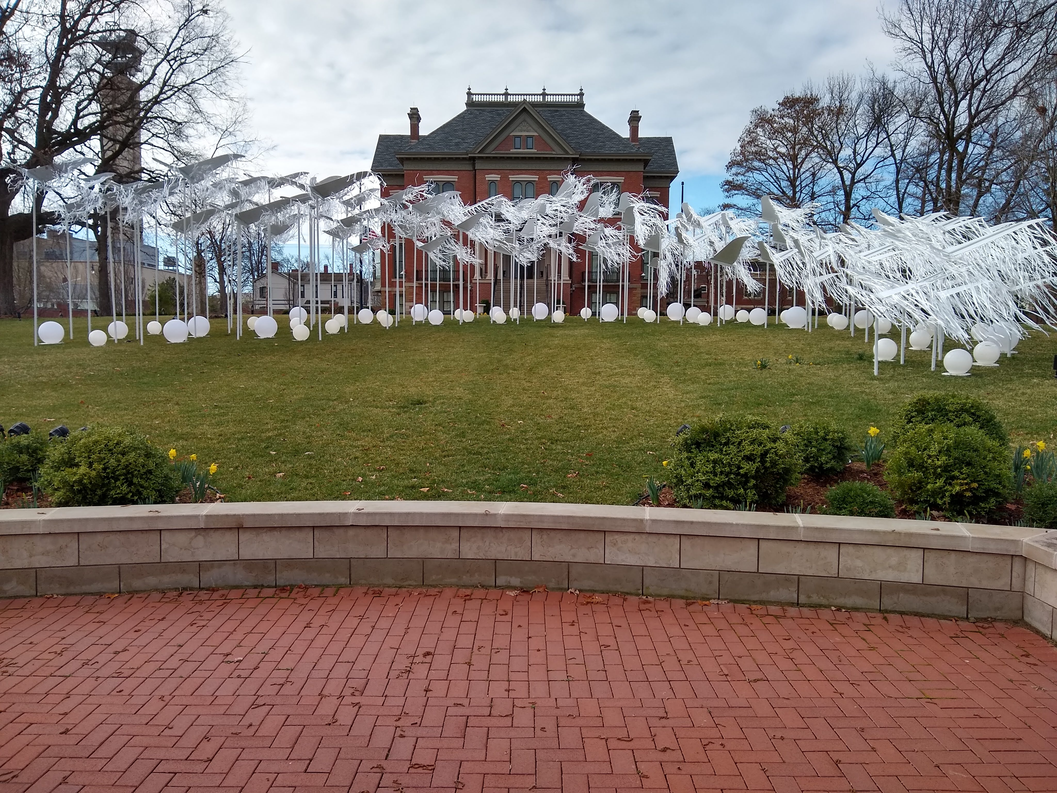 A picture of the Springfield, IL 2021 COVID-19 Memorial. The installation "pay[s] tribute to the more than 23,000 Illinoisans who died from COVID-19 across our 102 counties, as represented by 102 sets of wings. Together, the wings hold up over 5,500 ribbons, each representing 4 Illinoisans who lost their fight with this virus".