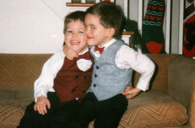 A childhood photo of the author & his brother in Christmas outfits (complete with bowties) sitting on their couch in their Buffalo home.