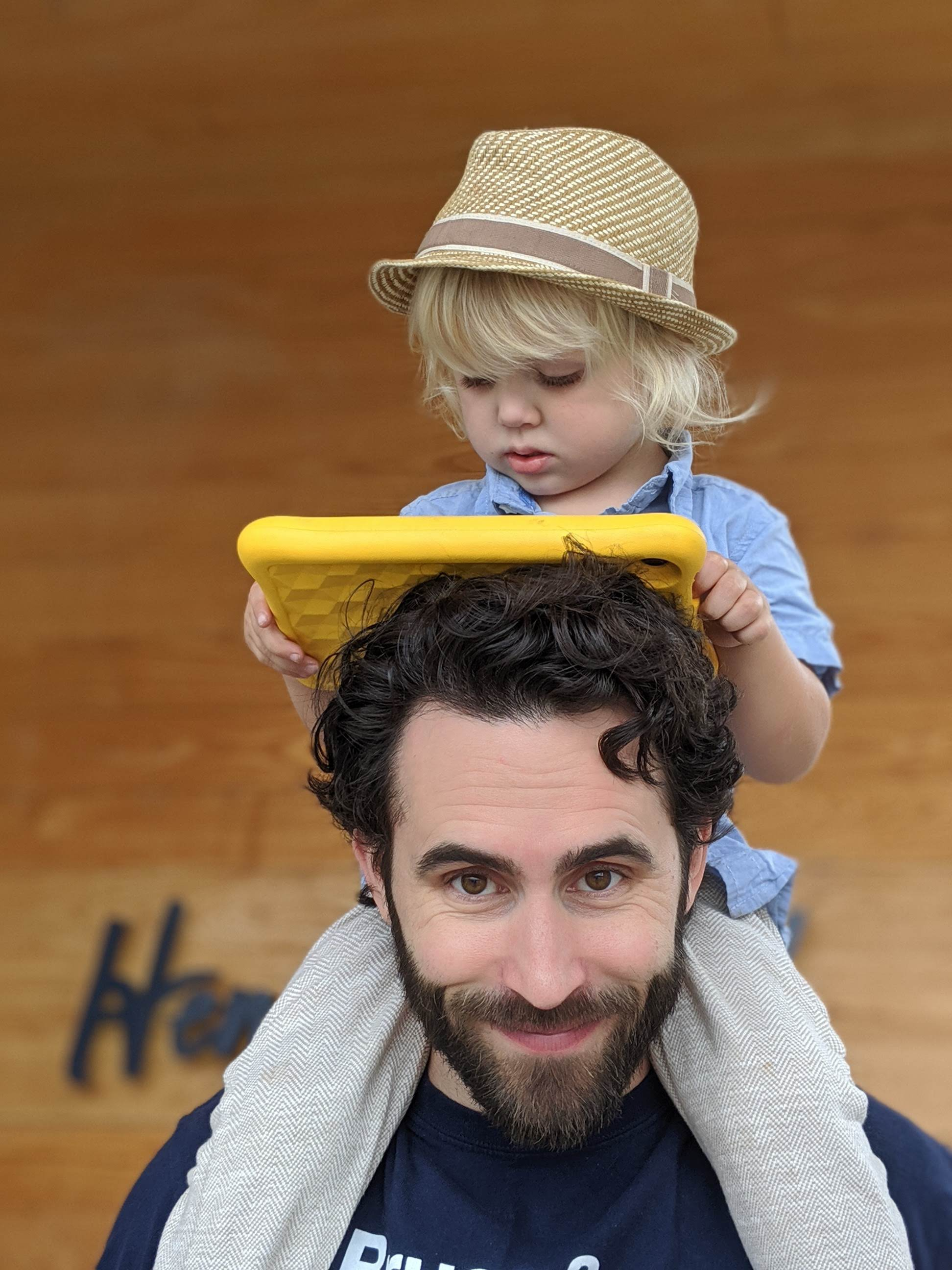 The author holding his godson, who's watching a show on his tablet, on his shoulders after brunch.