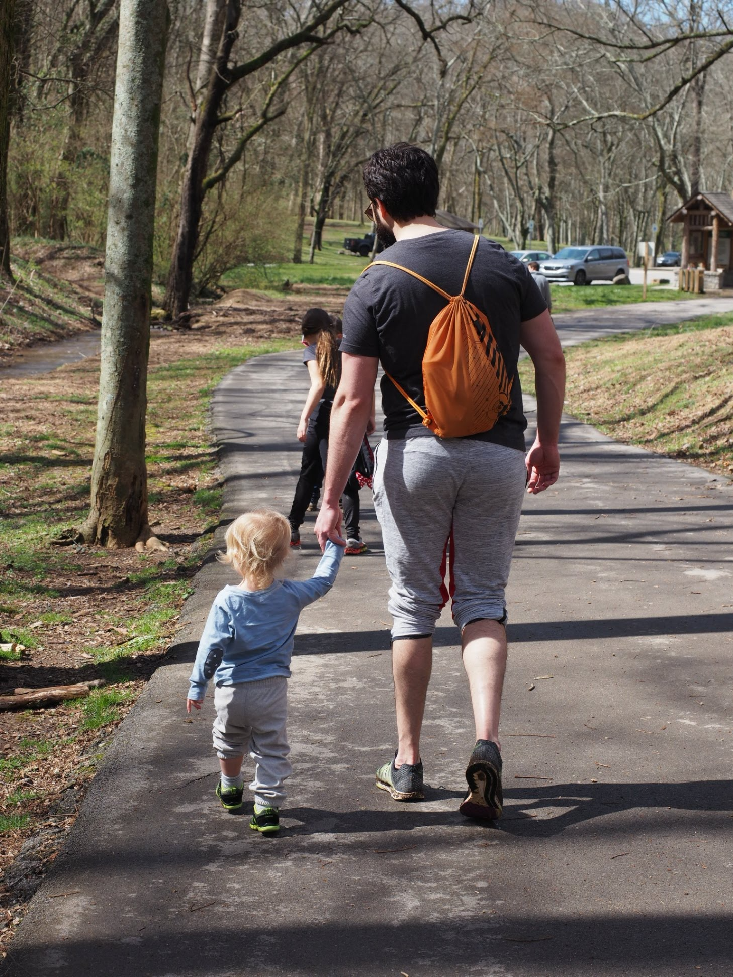 The author holding his godson's hand and walking along a trail in Nashville, possibly Percy Warner Park's Deep Well trailhead